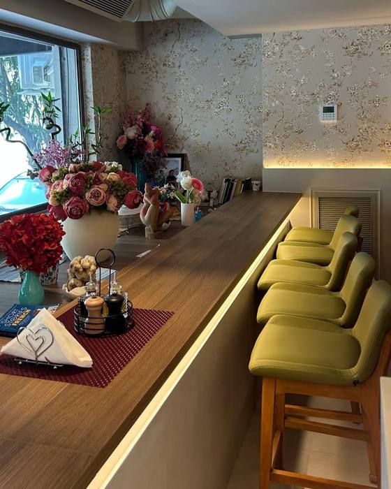 Banaku me karrige jeshile dhe lule të freskëta — the bar counter with green stools and fresh flowers